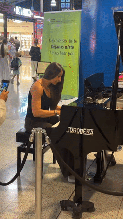 Woman plays piano performance at Barcelona airport terminal
