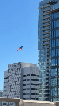 American flag and glass tower against clear San Diego sky