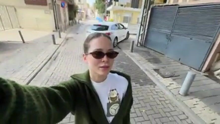 Woman takes selfies on cobblestone street in Jaffa, Tel Aviv