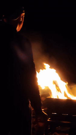Evening campfire observed in rural Belarus roadside setting