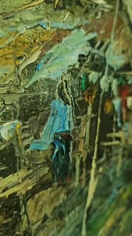 A close-up, angled view of an oil painting. The painting depicts a dense, verdant environment, possibly a hillside or jungle, with a cluster of rustic structures built into the terrain. The structures appear to be huts or shacks, constructed from natural materials like wood and thatch, and are nestled into the uneven landscape. Several small figures, rendered in a stylized manner, are visible within and around these structures. Some figures are dressed in colorful clothing, suggesting activity or daily life. Laundry hangs on lines stretched between the structures, adding a touch of domesticity to the scene. The painting is characterized by its thick, impasto application of paint, creating a textured and almost three-dimensional surface. The colors are rich and varied, with dominant greens, browns, and earthy tones, interspersed with brighter accents from the clothing and laundry. The overall impression is one of a vibrant, lived-in environment within a lush natural setting.