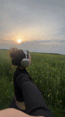 Woman records selfie walk through flowering fields at sunset