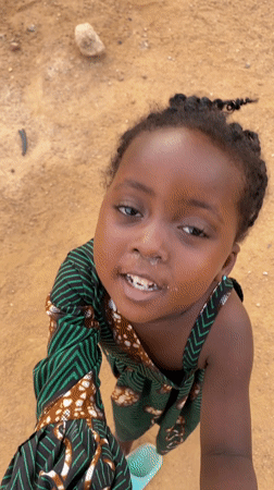 Nigerian village children play with pet monkey in yard
