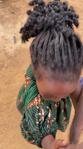 Nigerian village children play with pet monkey in yard