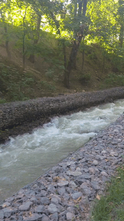 Gabion-walled stream cuts through green Almaty landscape