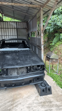 Black car mid-repair in open garage, Karon, Thailand