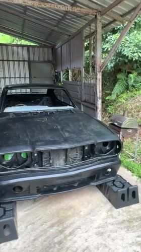 Black car mid-repair in open garage, Karon, Thailand