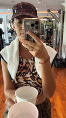 Woman takes gym mirror selfie with paper cups visible