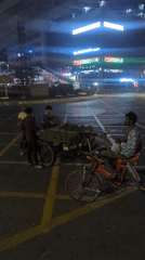 Nighttime street vendors with plant materials gather in Dhaka