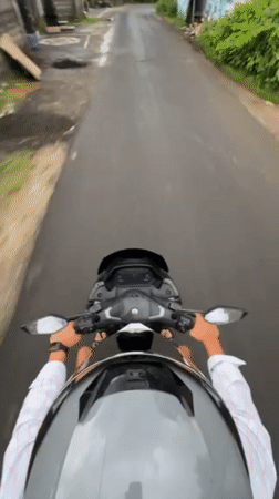 Motorcyclist travels narrow road in Kuta Selatan, Indonesia
