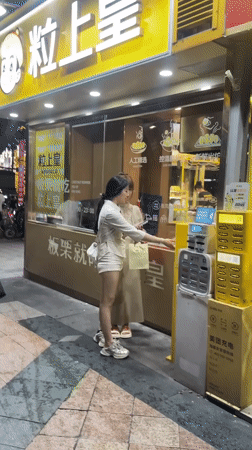 Women use charging station on Tianhe District sidewalk