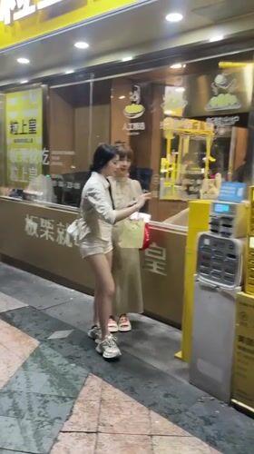 Women use charging station on Tianhe District sidewalk