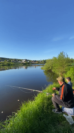 Adult and child fishing at pond in Markovo, Russia