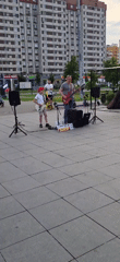 Father-son guitar duo performs street music outside apartment building