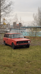 Man walks near red Lada in Krasnoyarsk field