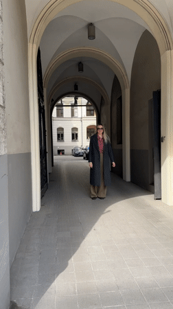 Woman in checkered shirt walks through Riga archway