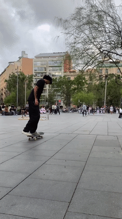 Skateboarder practices tricks in Barcelona public square during evening