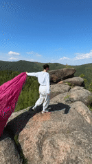 Woman photographs scenic valley from Stolby Nature Reserve rocks