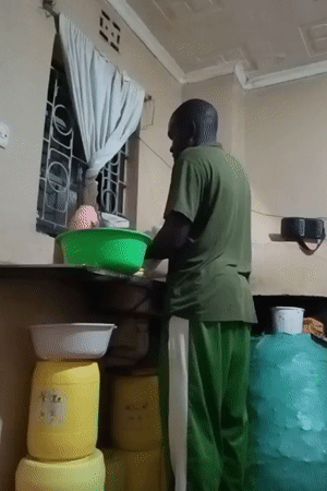 Man cooks and cleans in kitchen in Turbo, Kenya
