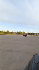 Teen rides red motorcycle in empty Russian parking lot