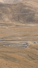 Vehicles navigate winding mountain road near Tashi Dzom, China