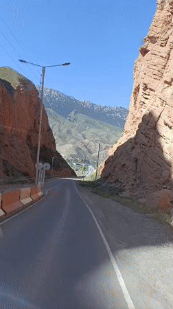 Paved canyon road winds through towering red rock formations