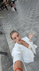 Woman takes selfies on Berlin street in white blazer