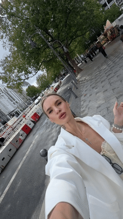 Woman takes selfies on Berlin street in white blazer