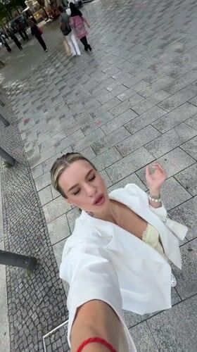 Woman takes selfies on Berlin street in white blazer