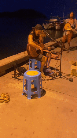 Street musician performs on pier in Baan Chaloklum, Thailand