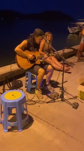 Street musician performs on pier in Baan Chaloklum, Thailand