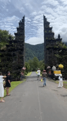 People gather at stone gate entrance in Indonesian valley