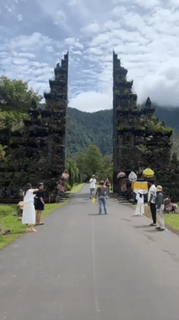 People gather at stone gate entrance in Indonesian valley