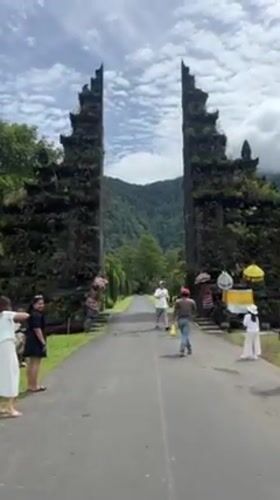 People gather at stone gate entrance in Indonesian valley