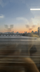 Train passenger films Seoul cityscape under colorful evening sky