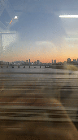 Train passenger films Seoul cityscape under colorful evening sky