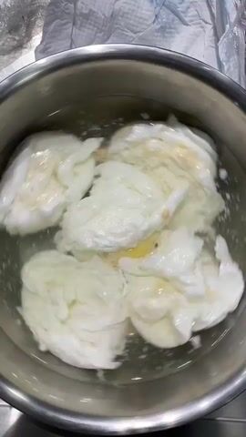 A stainless steel bowl containing several poached eggs sitting in water is visible. A person is heard chopping something behind the camera. The individual makes several chopping sounds. A wet napkin is visible in the background.