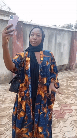 Woman takes selfie with purple phone in Rido, Nigeria