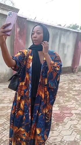 Woman takes selfie with purple phone in Rido, Nigeria