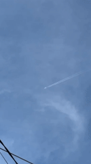 Child makes heart gesture, airplane leaves contrails overhead