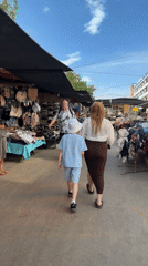 Woman and child browse sunny outdoor market stalls