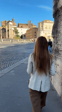 Woman walks past ancient ruins in Rome morning scene