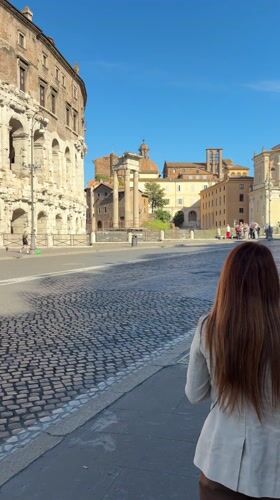 Woman walks past ancient ruins in Rome morning scene