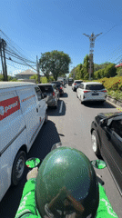 Motorcyclist rides through heavy traffic in Denpasar, Indonesia