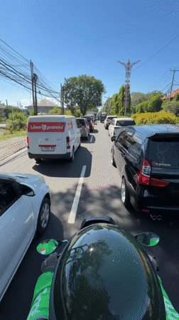 Motorcyclist rides through heavy traffic in Denpasar, Indonesia