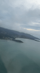 Passenger films aerial view over Thailand waters from airplane window