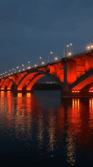 Red-lit Kommunalny Bridge captured across Krasnoyarsk at dusk