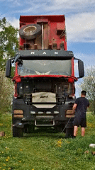 Man repairs and paints truck in dandelion field