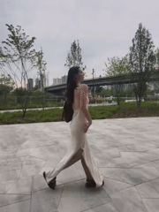 Woman in cream dress moves through Tyumen park locations