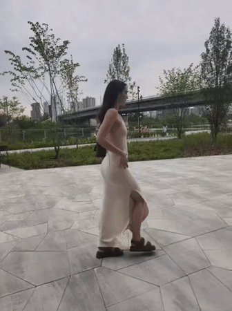 Woman in cream dress moves through Tyumen park locations